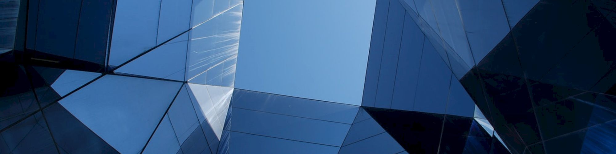 Geometric view of skyscraper glass reflections creating a symmetrical frame around the sky, conveying modern architectural aesthetics.