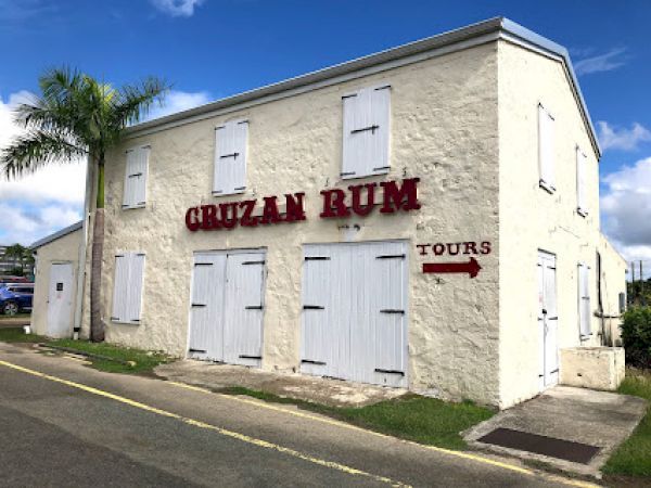 A cream-colored building with "CRUZAN RUM" on it and a red arrow pointing to "TOURS" appears in the image.